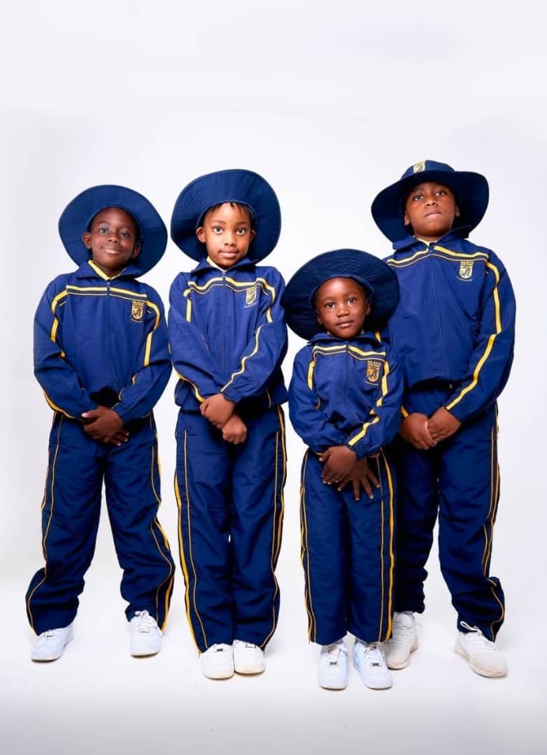 Four schoolchildren wearing navy and gold NECST winter tracksuits with hoods